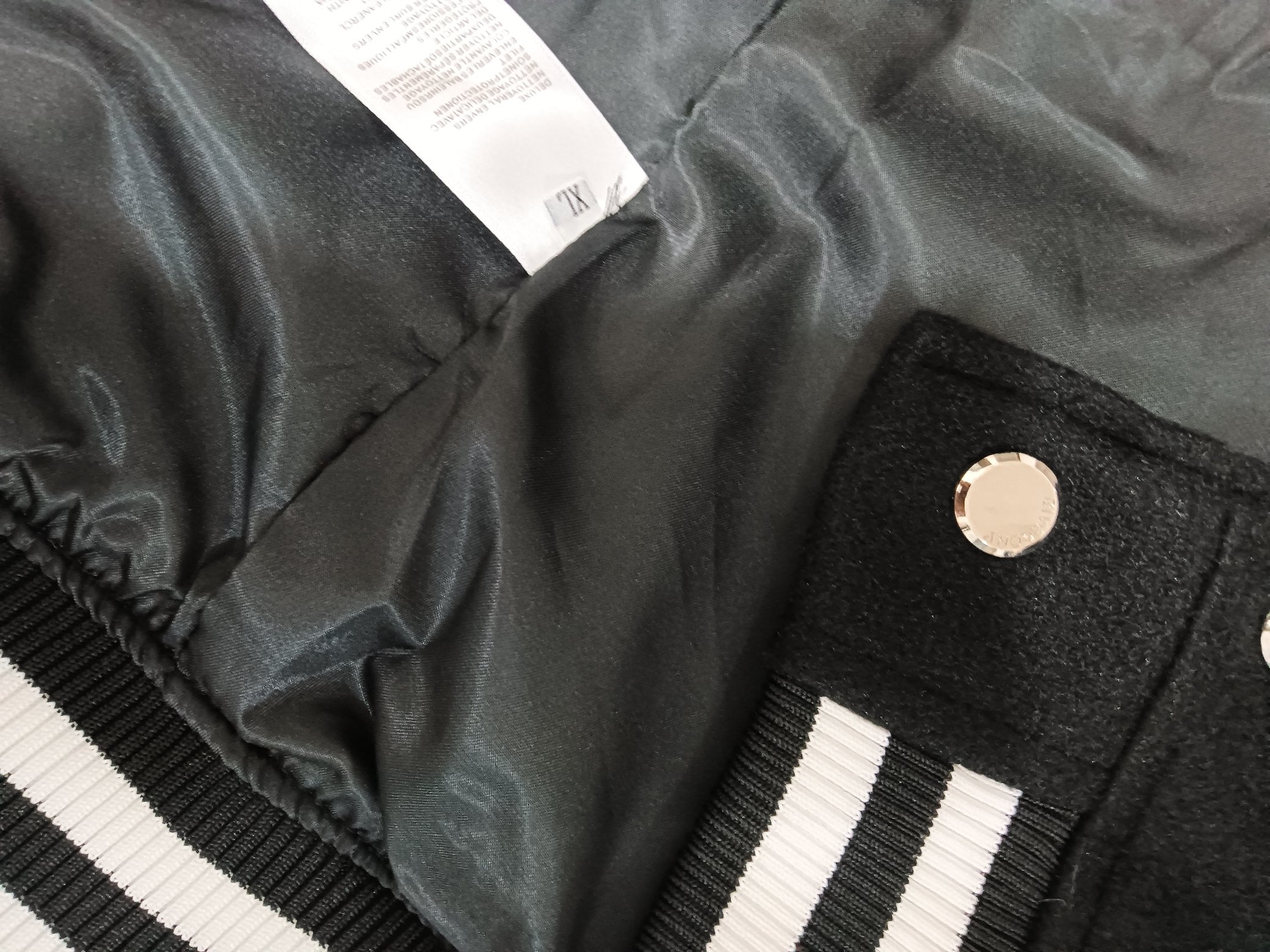 Givenchy varsity jacket collar and snap placket, black fabric with striped ribbing