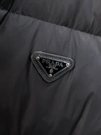 Close-up of embroidered triangular logo patch on dark puffer vest