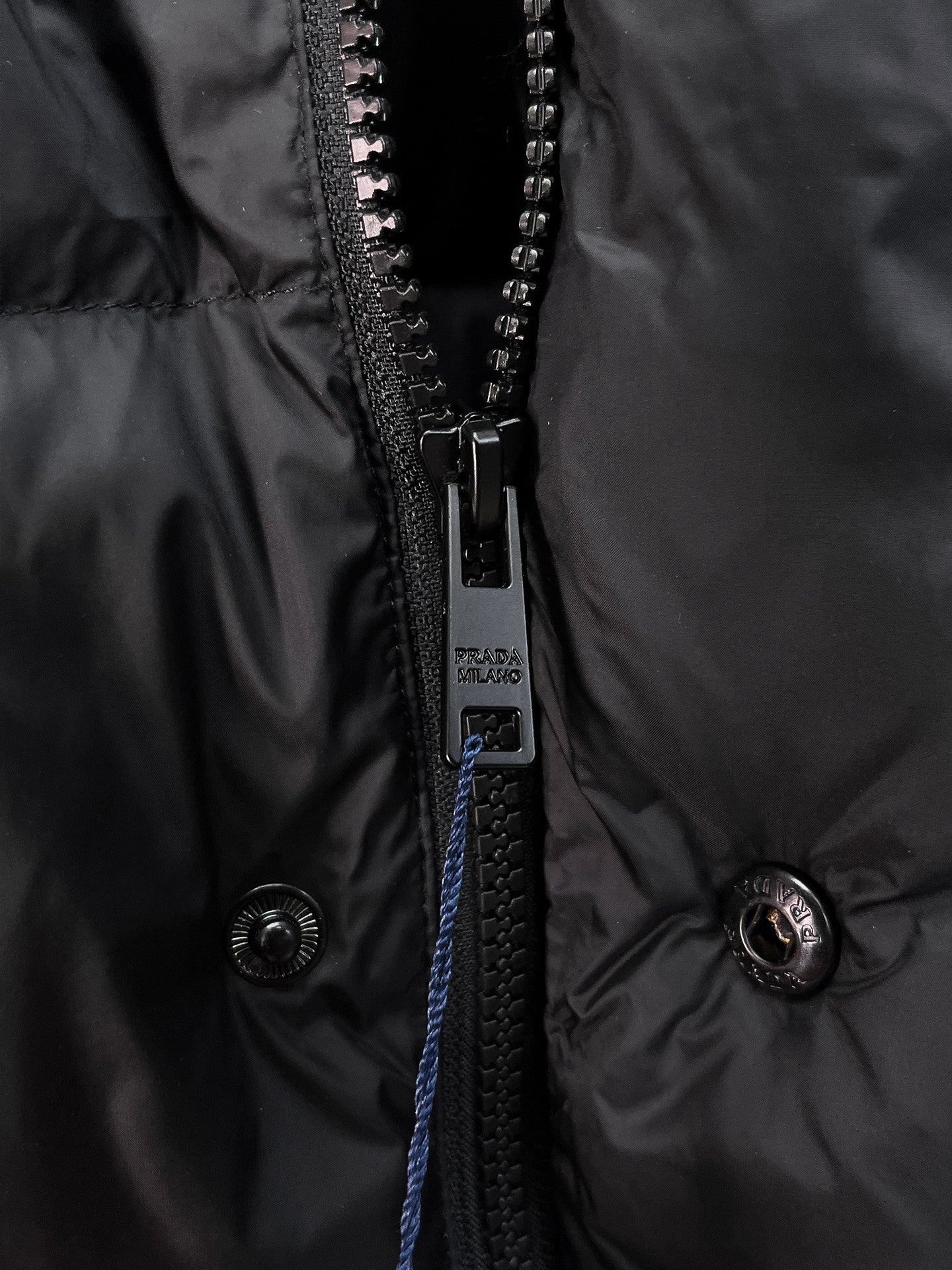 Close-up of dark zipper and snap buttons on hooded puffer vest
