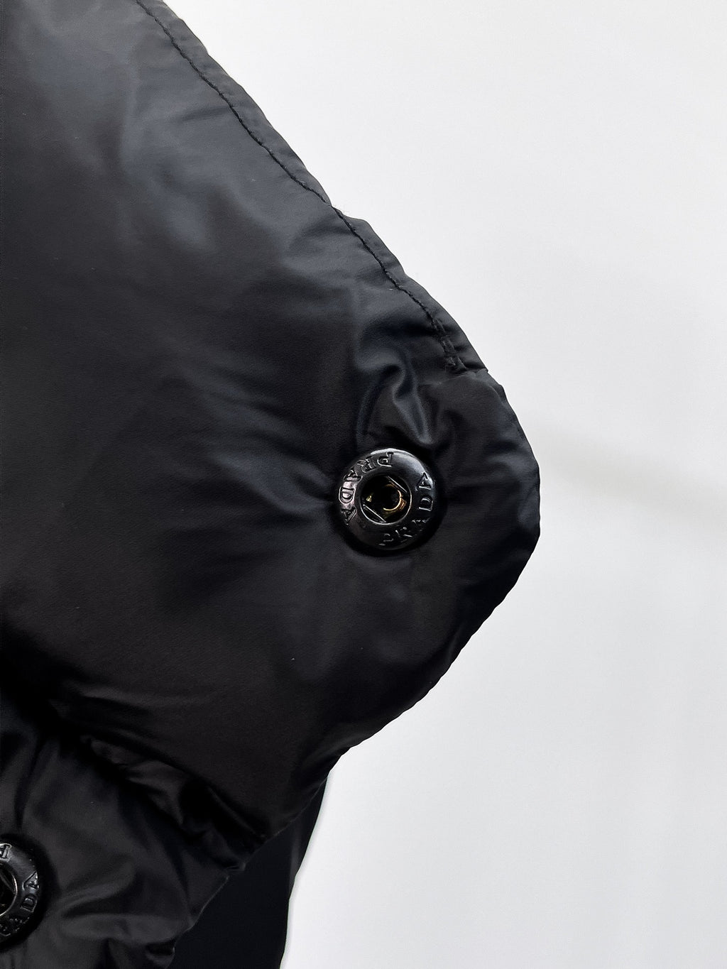 Close-up of dark puffer vest arm with round snap button