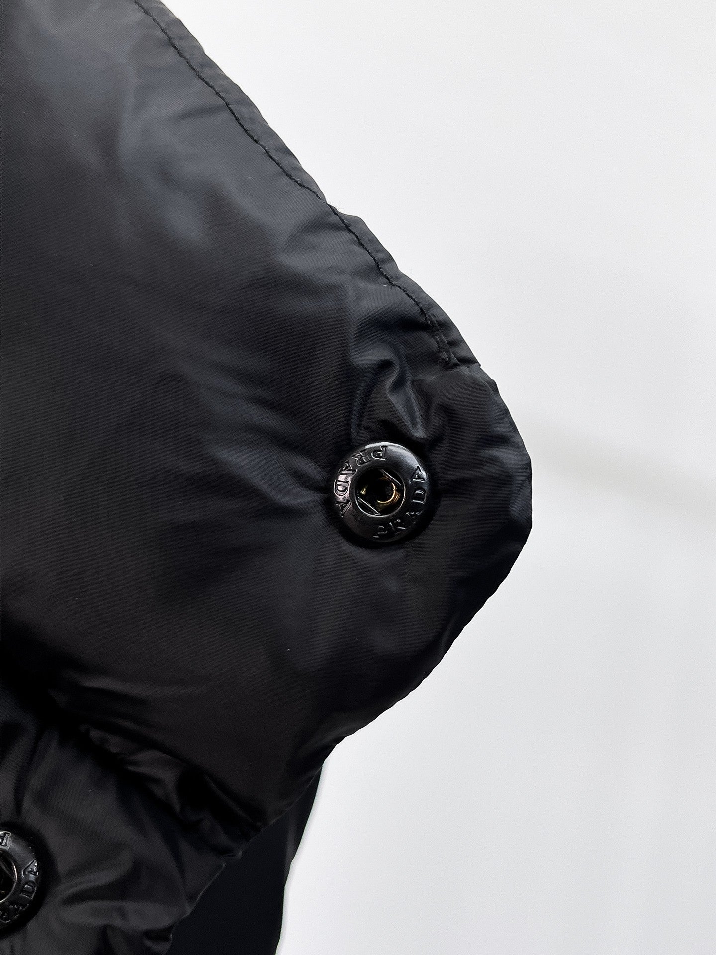 Close-up of dark puffer vest arm with round snap button
