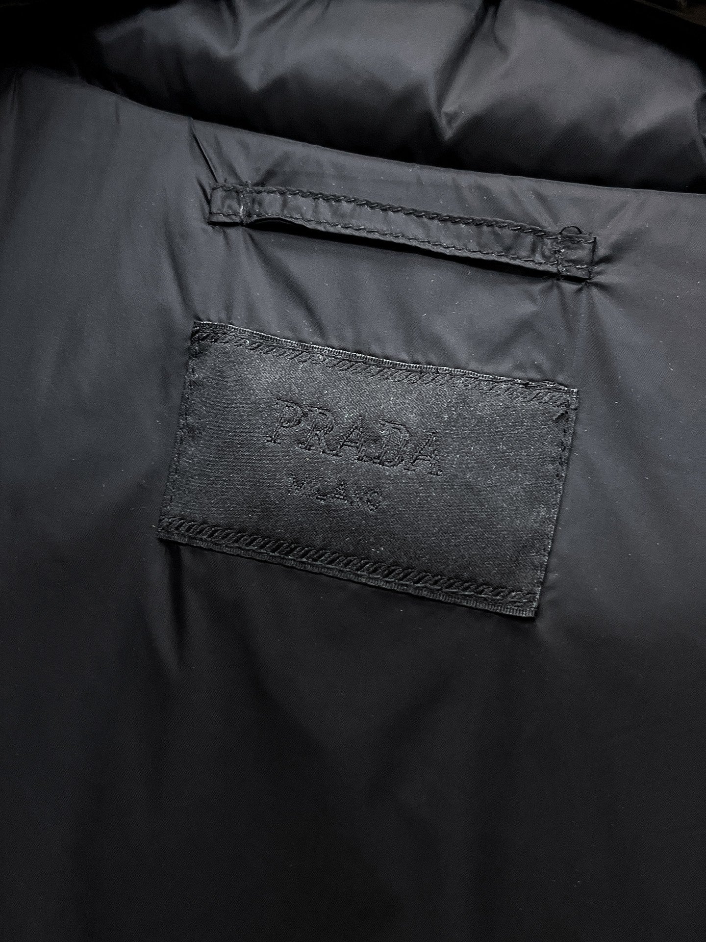 Close-up of rectangular fabric label inside dark puffer vest