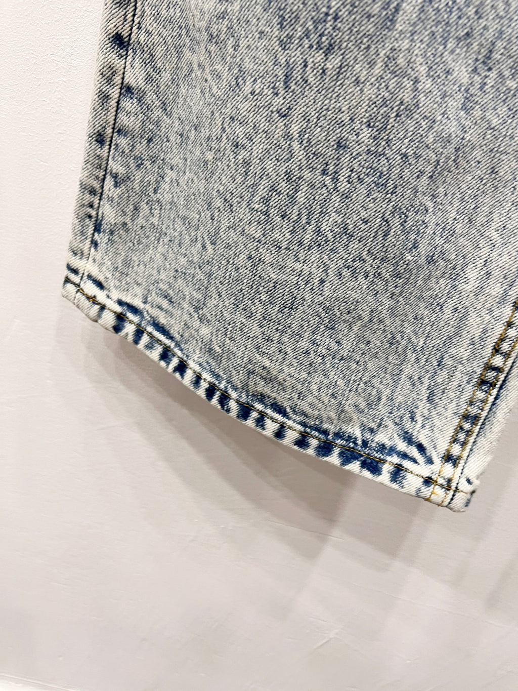 Denim hem close-up with blue patterned stitching and folded cuff edge