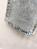 Denim hem close-up with blue patterned stitching and folded cuff edge