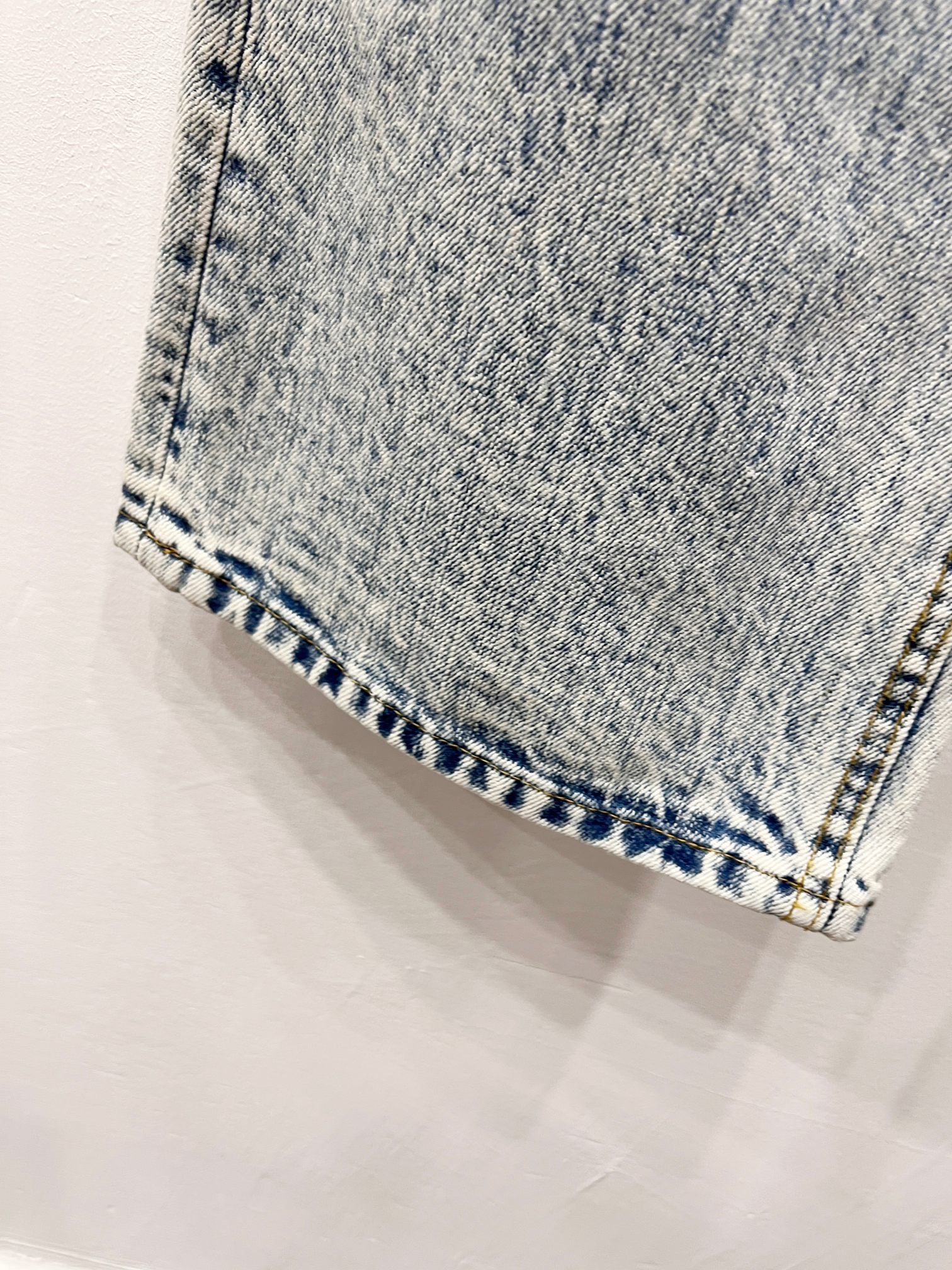 Denim hem close-up with blue patterned stitching and folded cuff edge