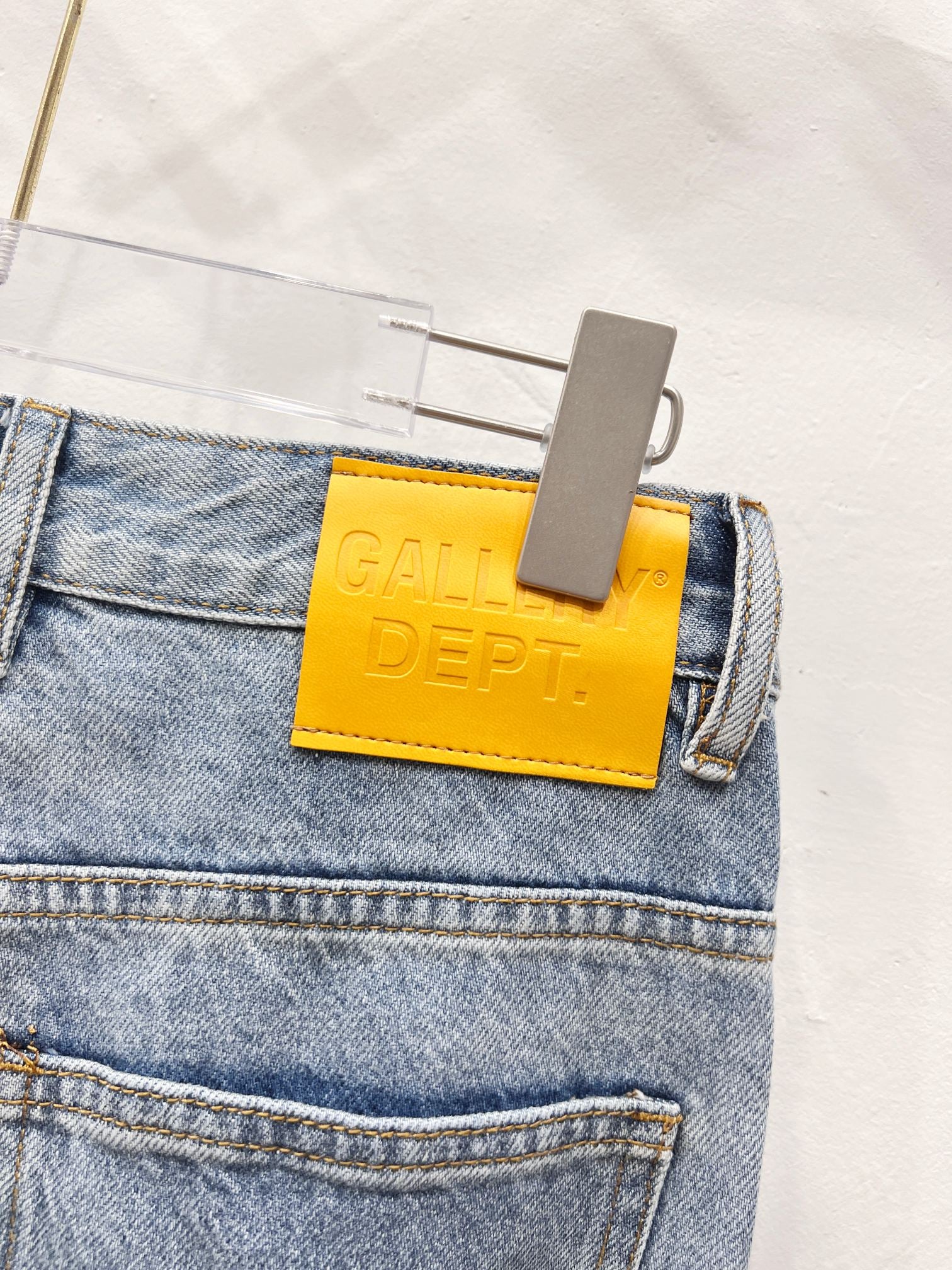 Denim pants close-up: yellow GALLERY DEPT. leather patch at waistband