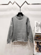 Gray knit sweater with crew neck and black distressed patterns on sleeves
