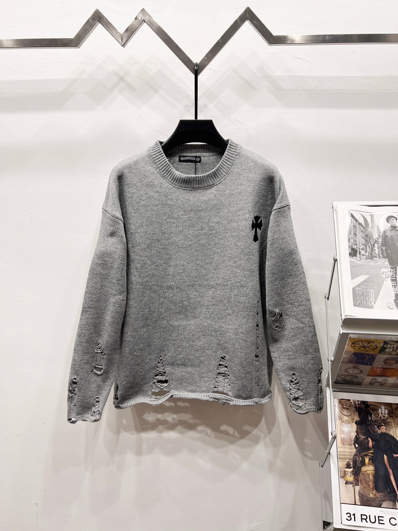 Gray knit sweater with crew neck and black distressed patterns on sleeves