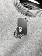 Gray knit sweater neckline with hanging brand tag at collar