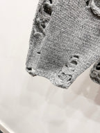 Gray knit sweater cuff close-up with distressed holes and frayed edge