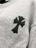 Gray knit sweater close-up of black cross-like emblem on chest