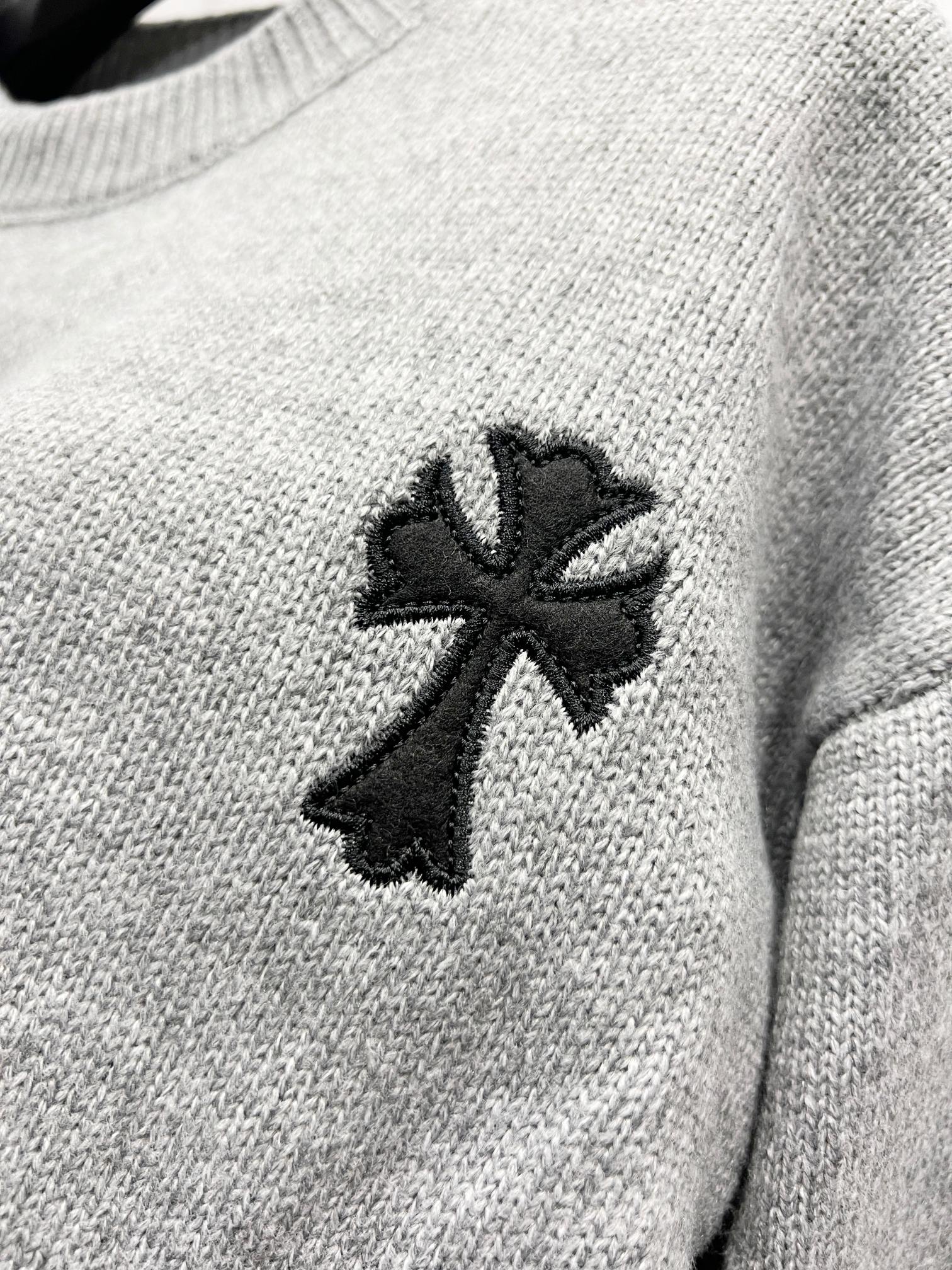 Gray knit sweater close-up of black cross-like emblem on chest