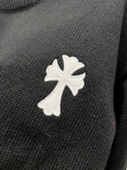 Black knit sweater with large white cross-flower applique on the front