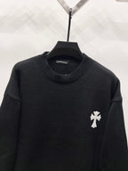 Black knit crewneck sweater with ribbed collar and small white crest patch on sleeve