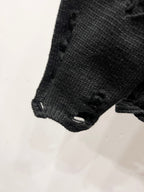 Black knit sweater sleeve hem with distressed stitching and frayed cuff edge