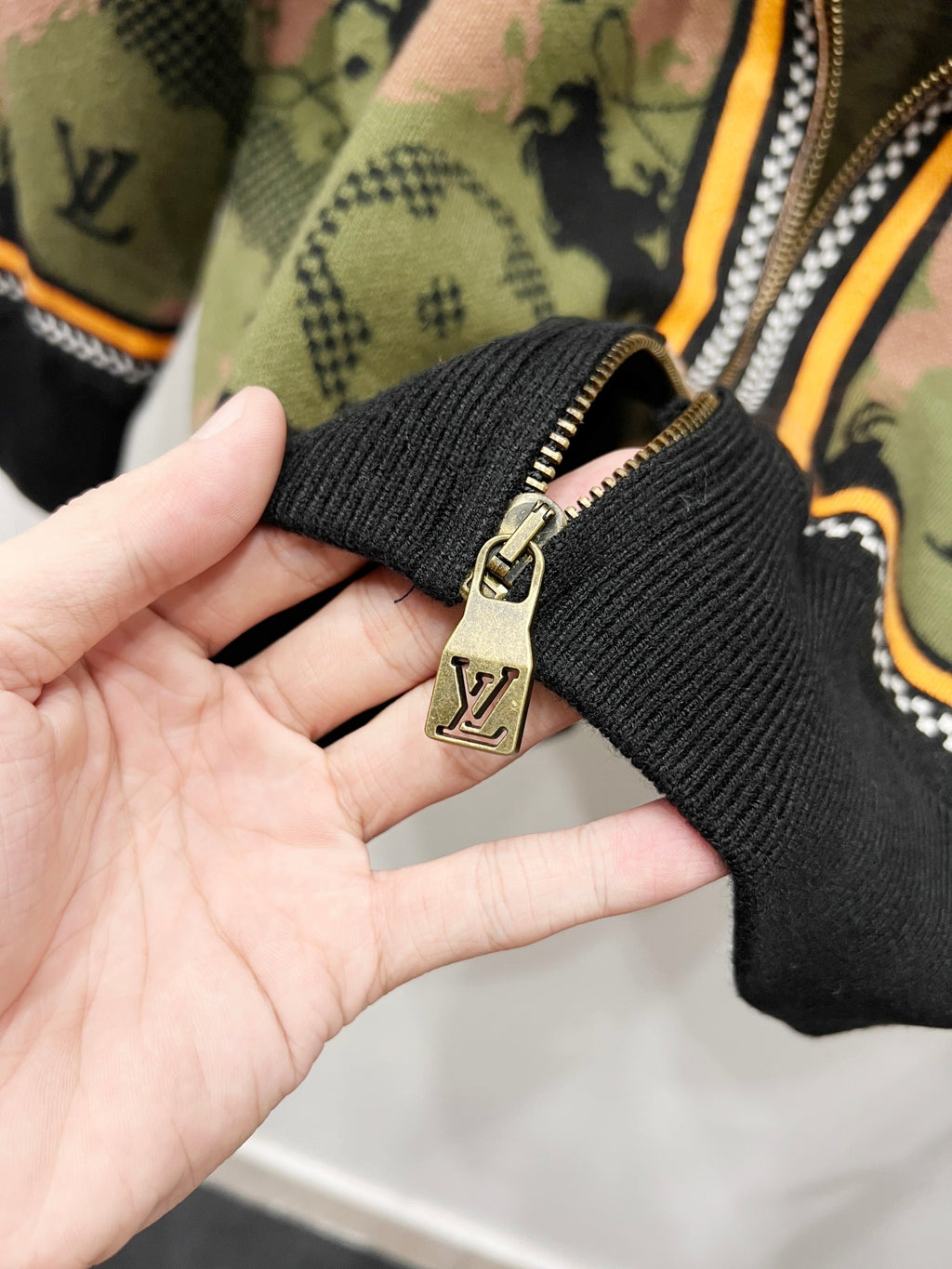 Zip-up jacket cuff with black rib knit and gold zipper pull