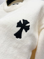 Cream knit sweater with black clover-shaped embroidered applique on the front