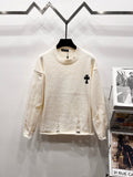 Cream long-sleeve knit sweater with ribbed crew neck and small black clover logo on chest