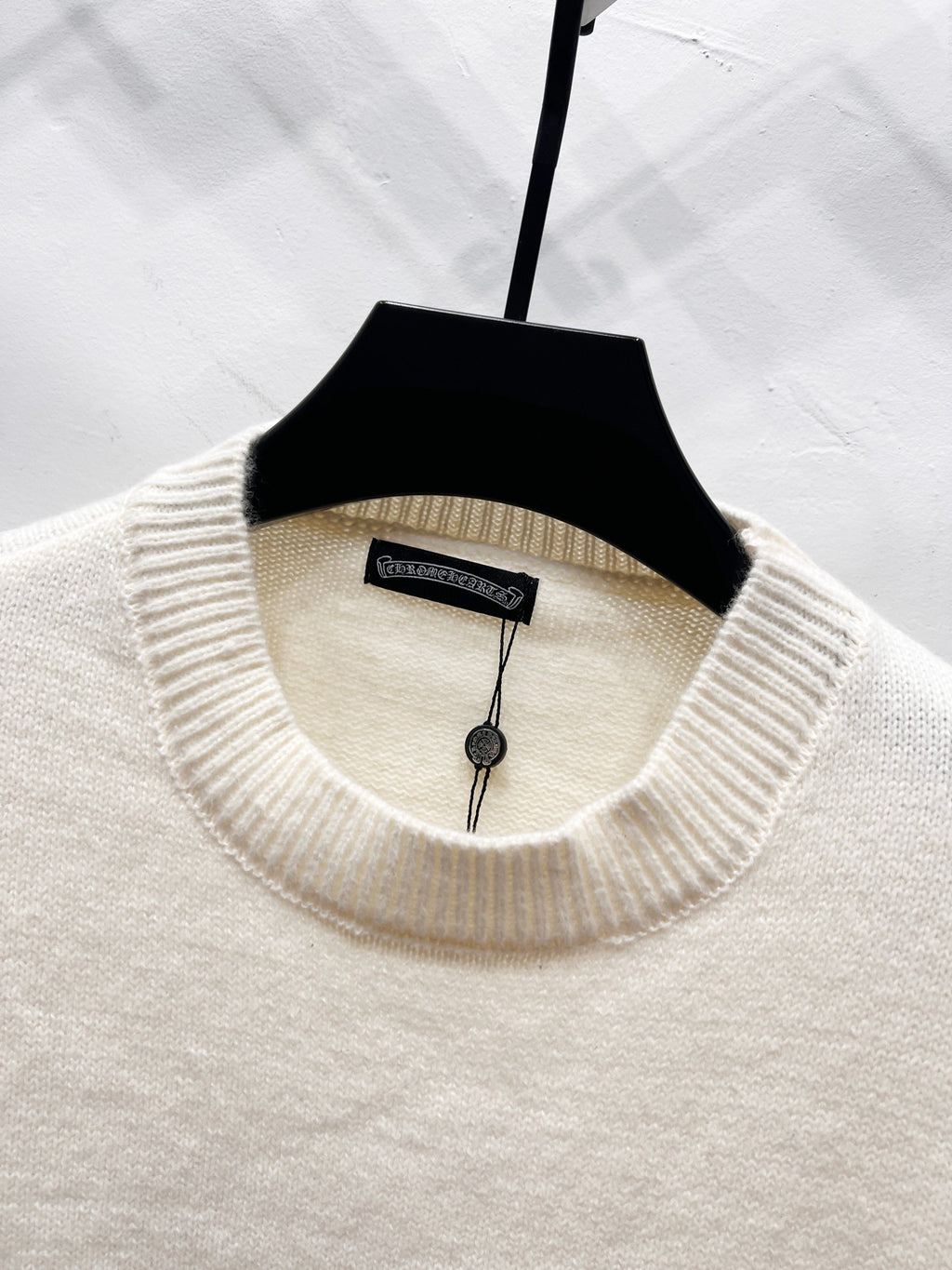 Cream sweater crew neck with ribbed collar and attached inner label on hanger