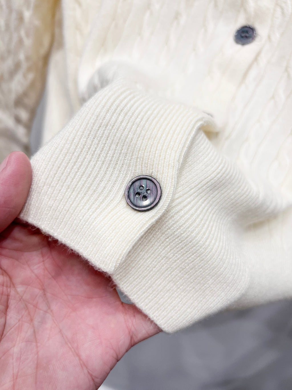 Cream knit cardigan sleeve cuff with round dark button detail