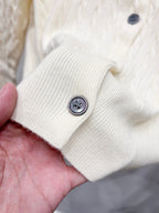 Cream knit cardigan sleeve cuff with round dark button detail