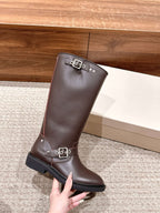 Golden Goose dark brown leather boot held up by hand, front buckle strap detail