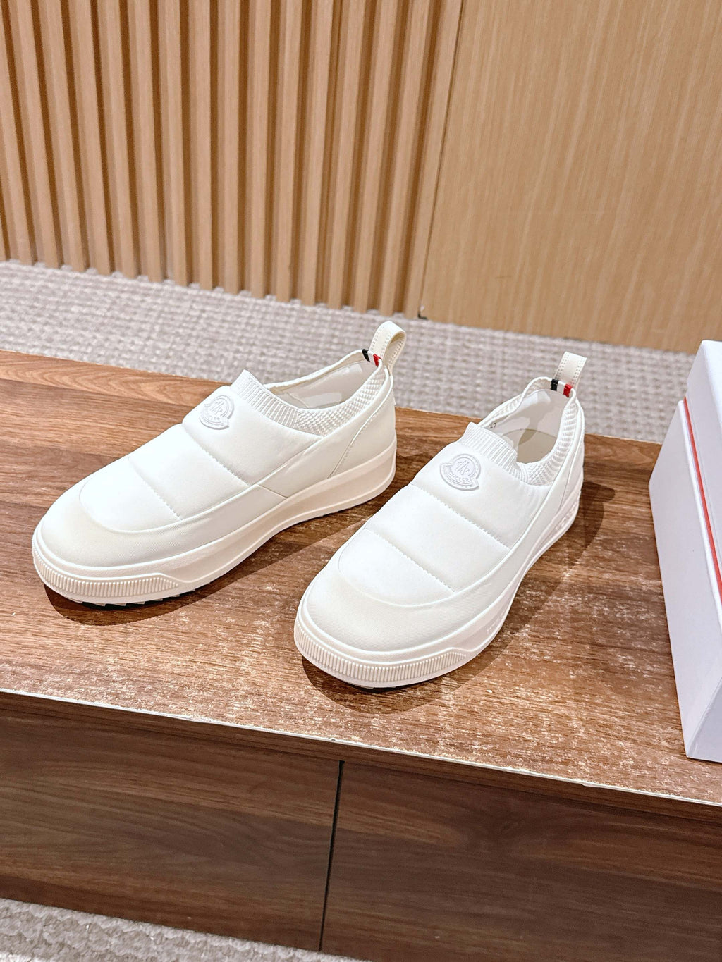 Moncler white slip-on sneakers shown from the side, cushioned sole