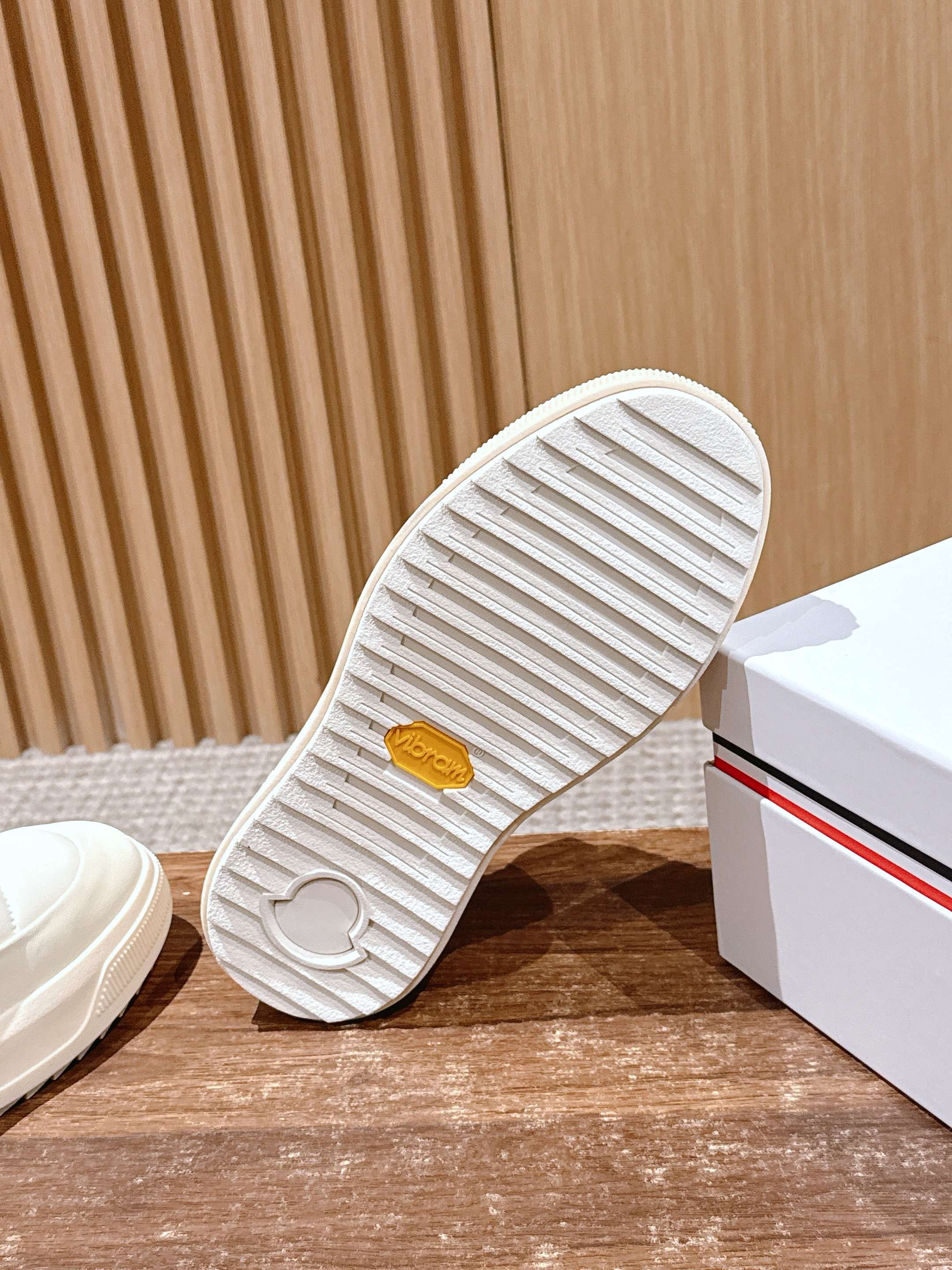 Moncler white slip-on sneaker outsole view, ribbed tread and logo on heel