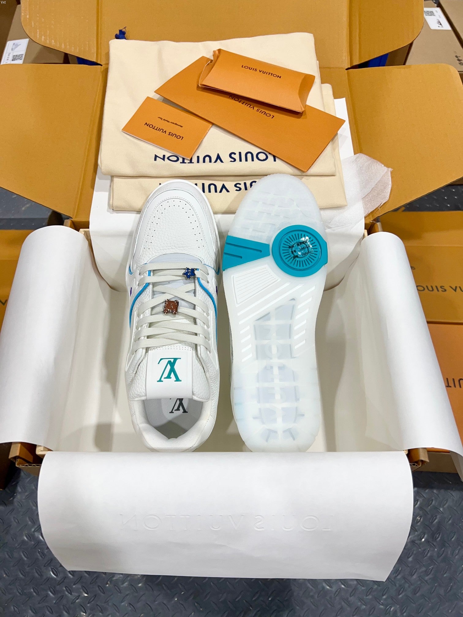 White Louis Vuitton trainer shoes with blue laces and blue circular heel logo marking.