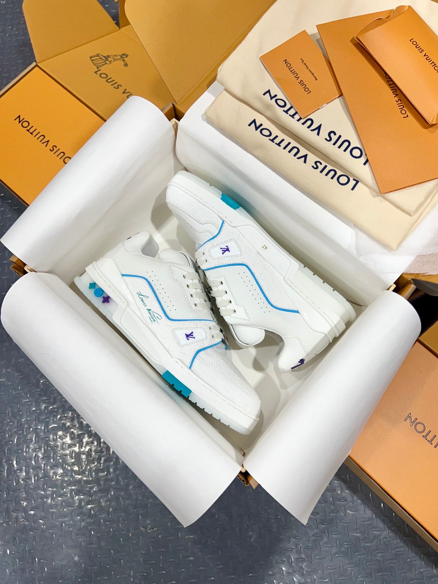 White Louis Vuitton trainer shoes with blue trim, lace details, and textured side panels.