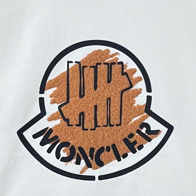 Moncler logo patch on white sweatshirt with brown textured print and black outline