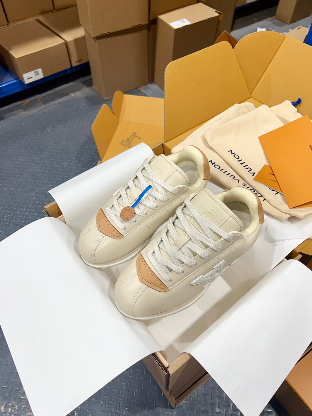 Cream low-top sneakers with tan side panels, white laces, and chunky rubber sole