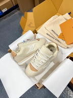 Cream low-top sneakers with tan accent panels, white laces, and side logo detail