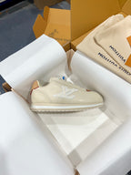 Cream low-top sneakers with tan side panels and white logo on the side
