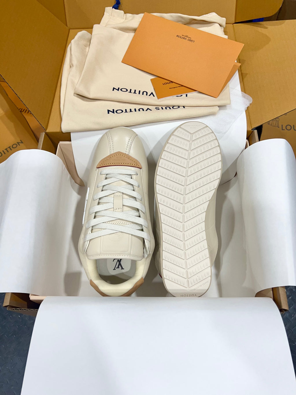 Cream low-top sneakers with visible outsole tread and tan heel and lace area accents