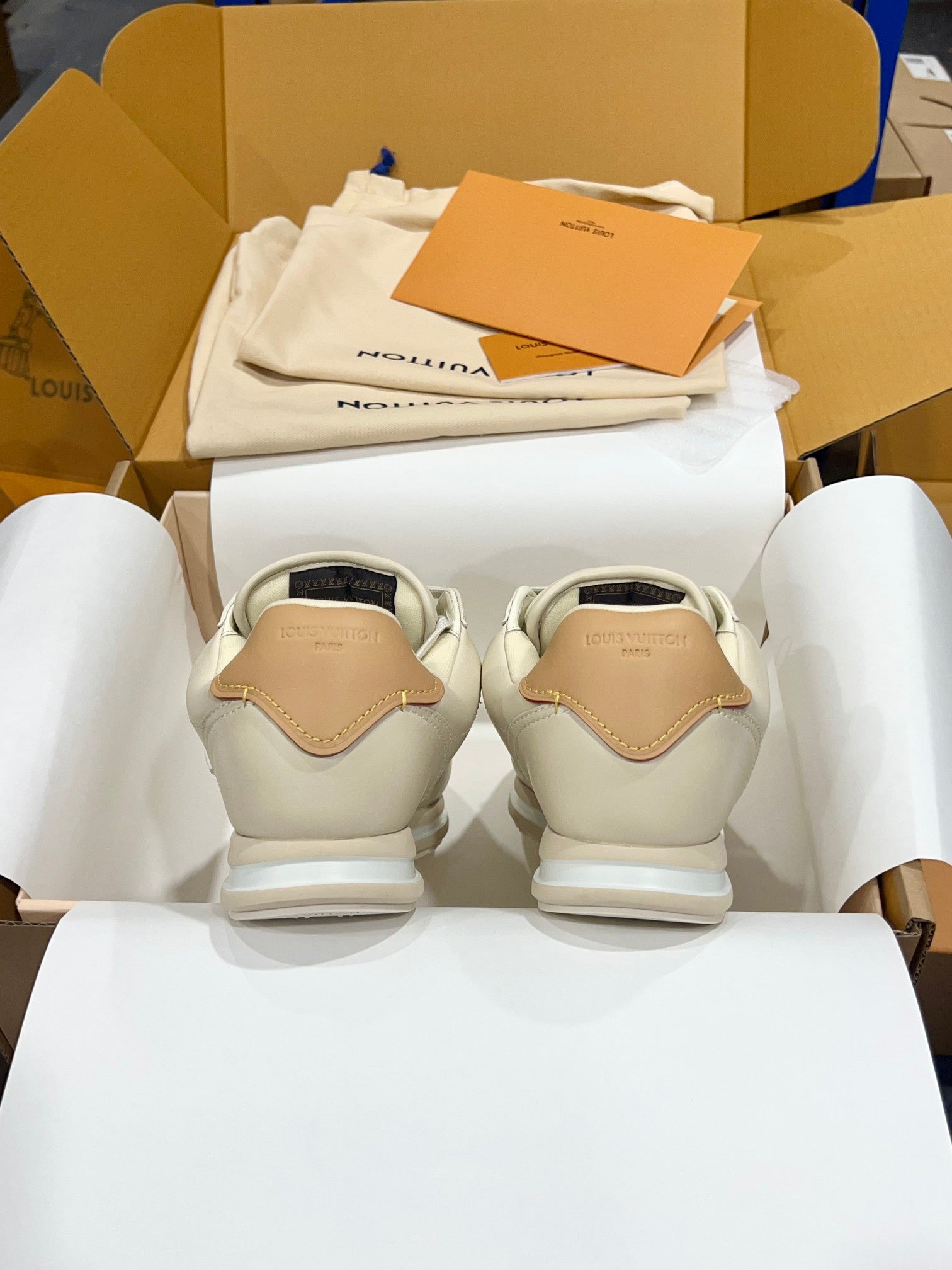 Back view of cream low-top sneakers with tan heel tabs and white rubber midsoles
