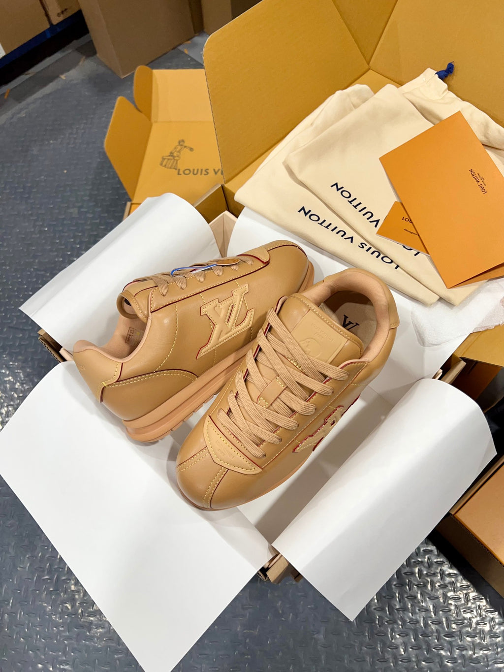 Tan leather low-top sneakers with embossed LV monogram on side and braided laces