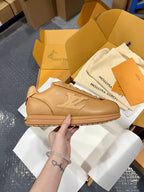 Tan leather low-top sneakers with lace-up front and raised emblem detail