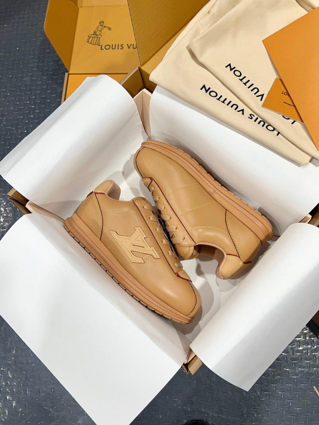 Tan leather low-top sneakers with thick rubber sole and logo patch on side