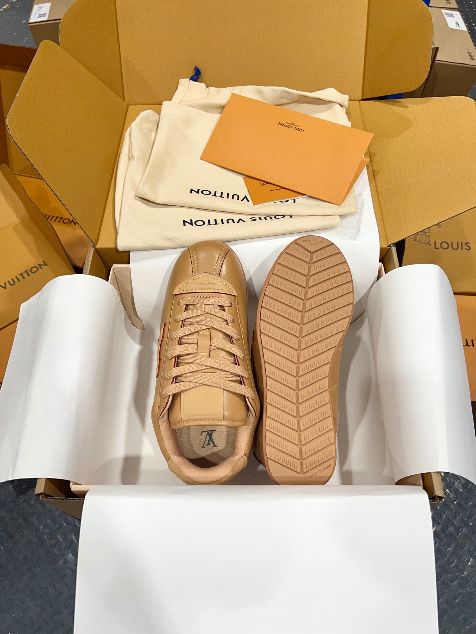 Tan lace-up low-top sneakers with textured rubber sole and side emblem visible
