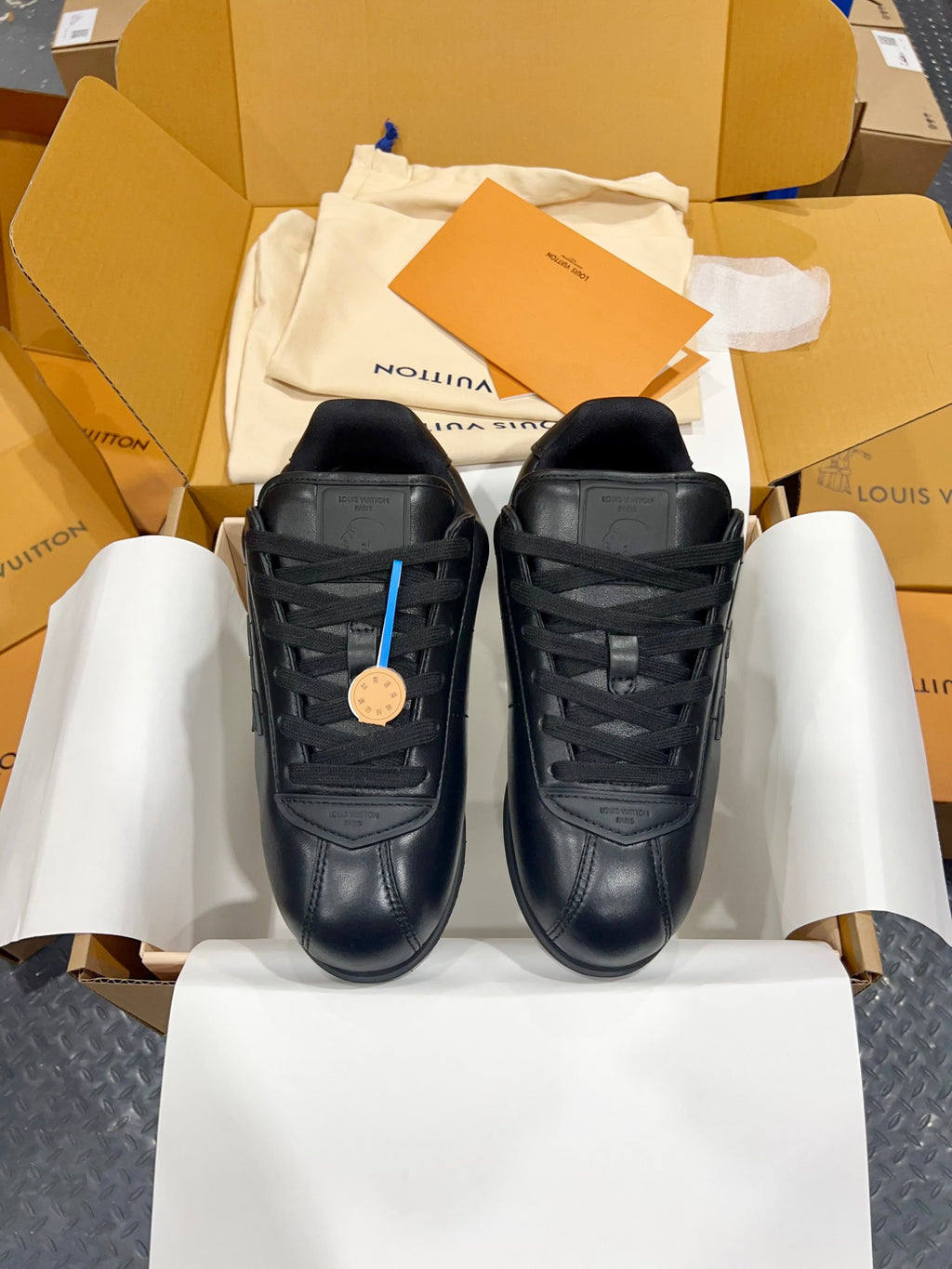 Pair of black Louis Vuitton lace-up sneakers on white tissue paper, flat view