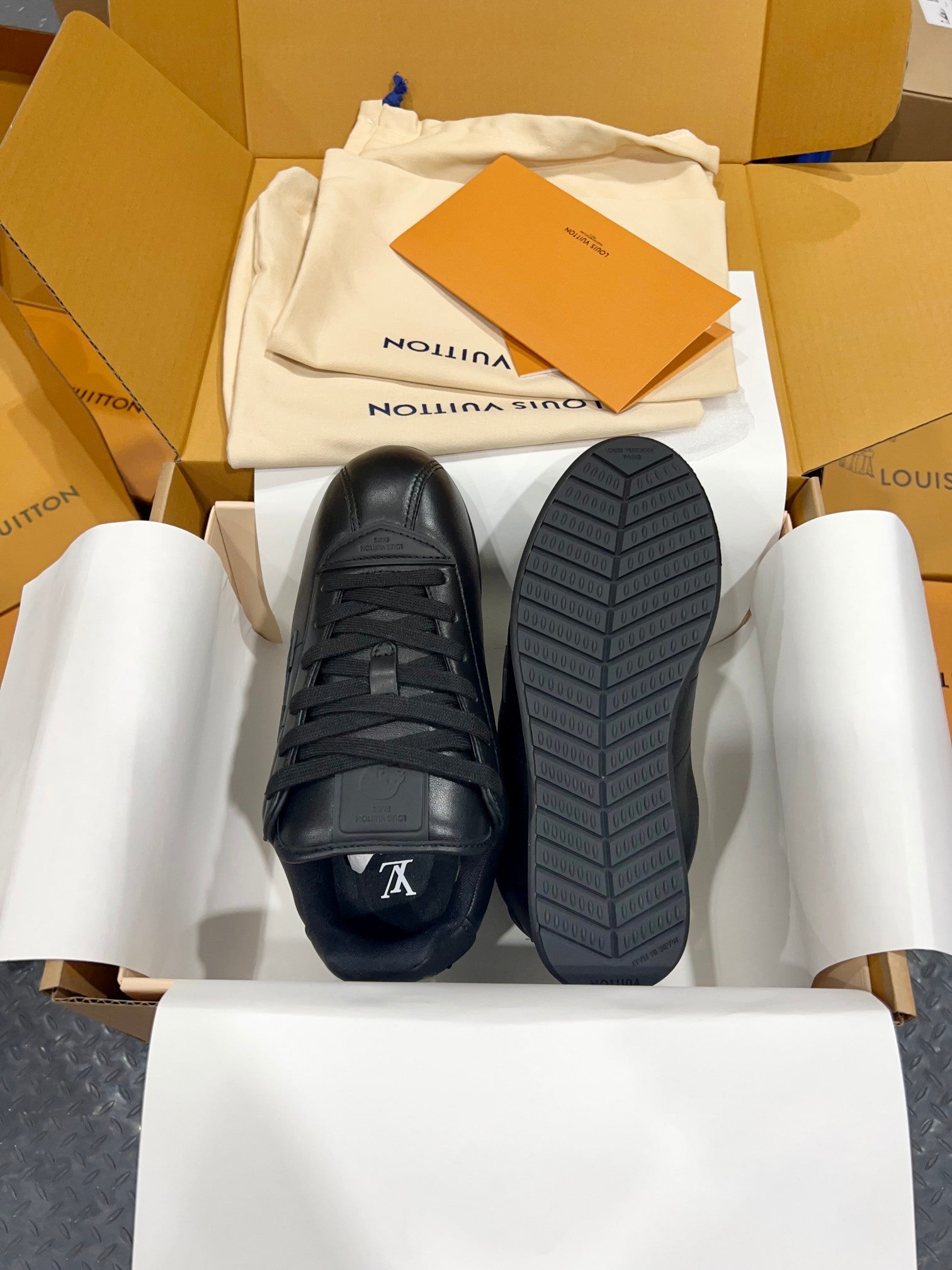 Black Louis Vuitton lace-up sneakers with treaded rubber sole, bottom visible