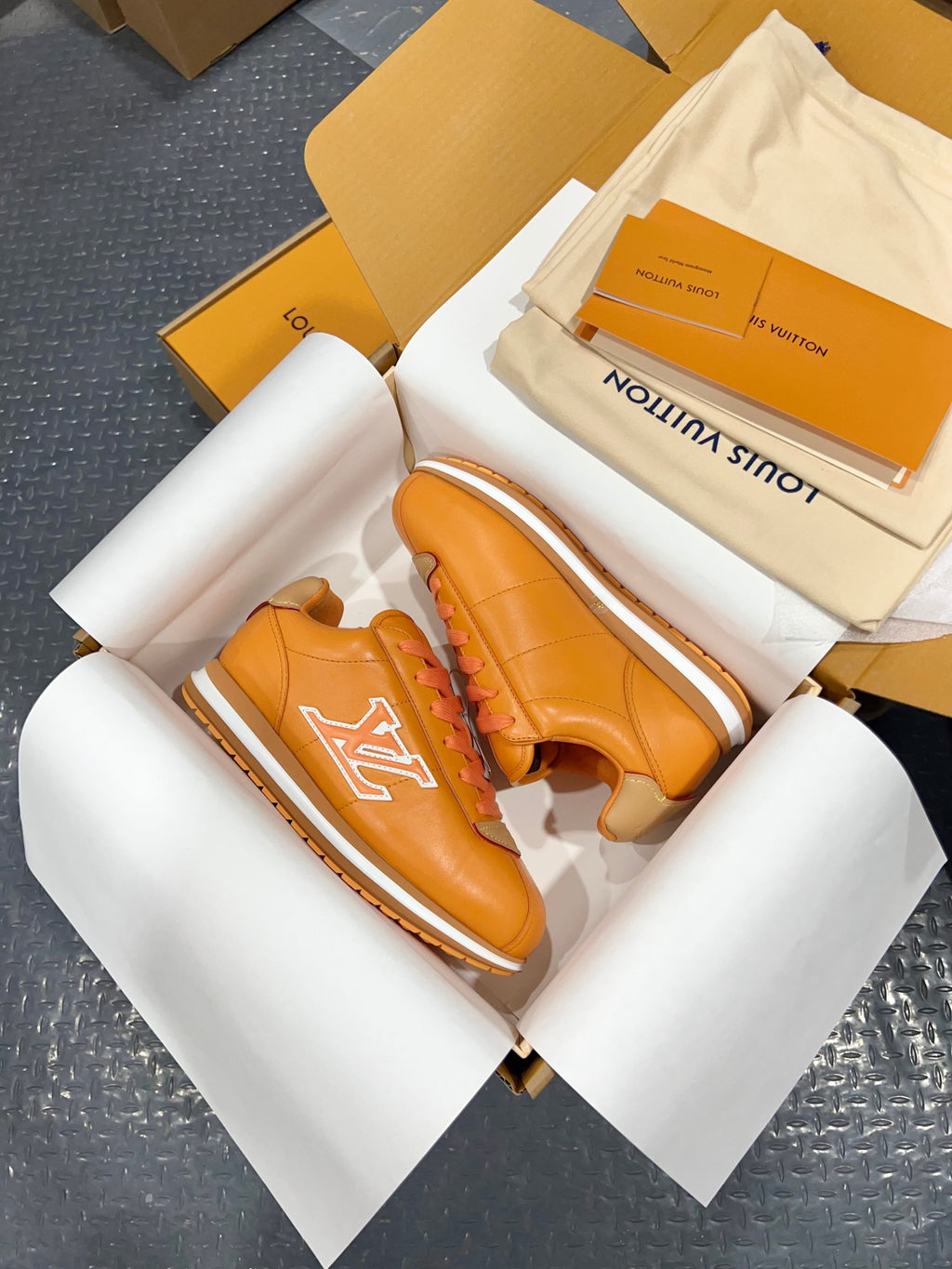 Louis Vuitton unisex sneakers orange leather with white LV logo, angled view in open box