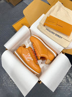 Louis Vuitton unisex sneakers orange leather with white LV logo, angled view in open box