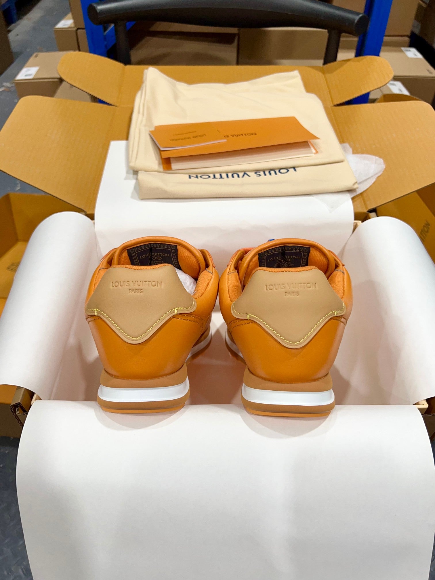 Louis Vuitton unisex sneakers back view, orange uppers with beige heel panels and white soles