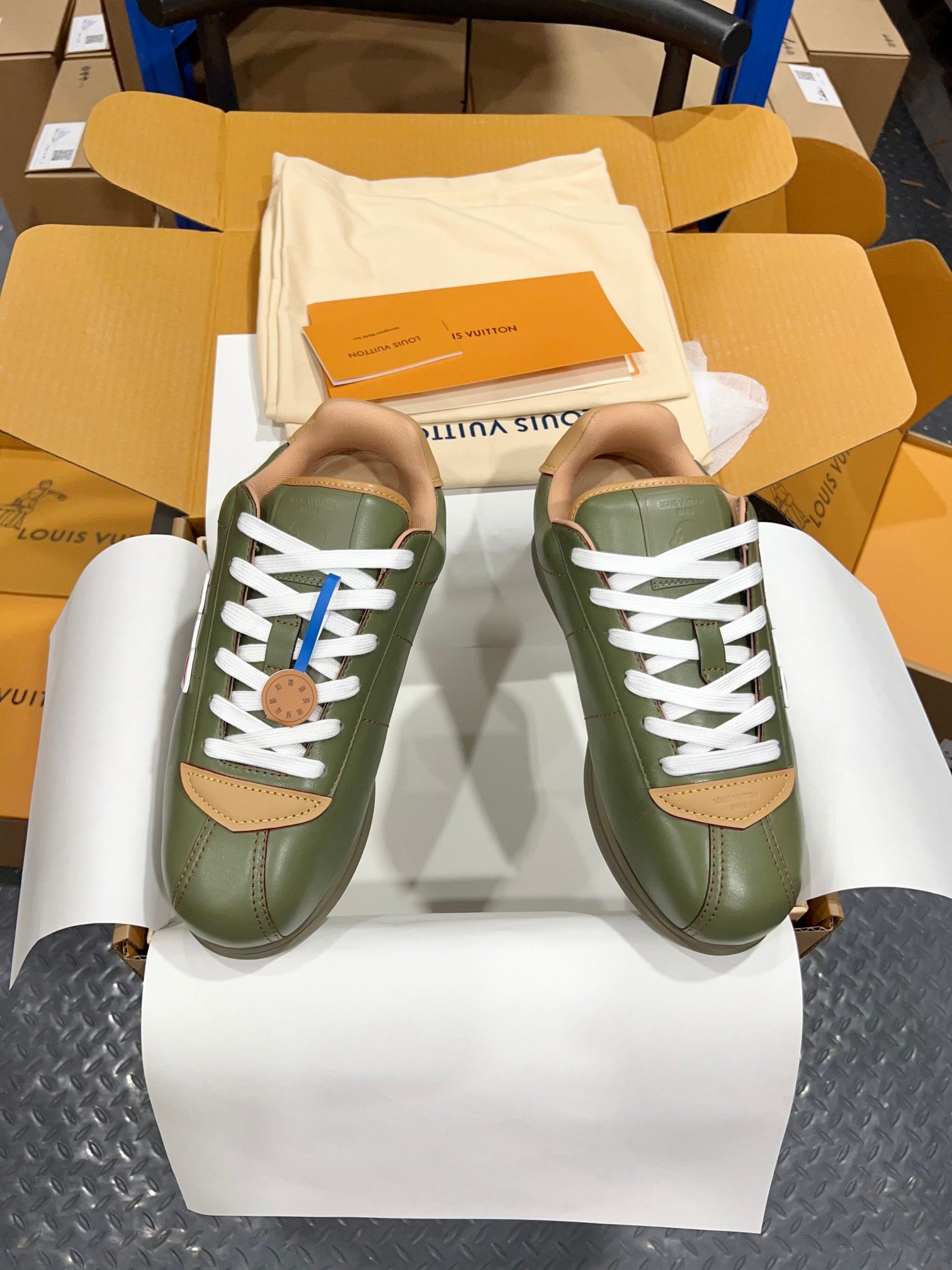 Green leather sneakers with white laces and tan side panels, LV logo visible