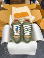 Green leather sneakers with white laces and tan logo patches in shoebox