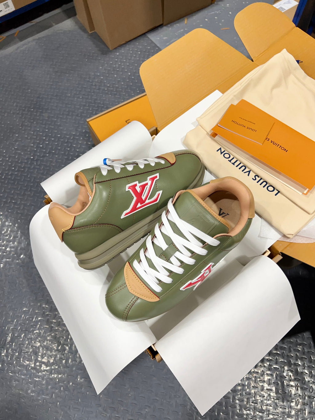 Green leather sneakers with white laces and red LV side logo on box