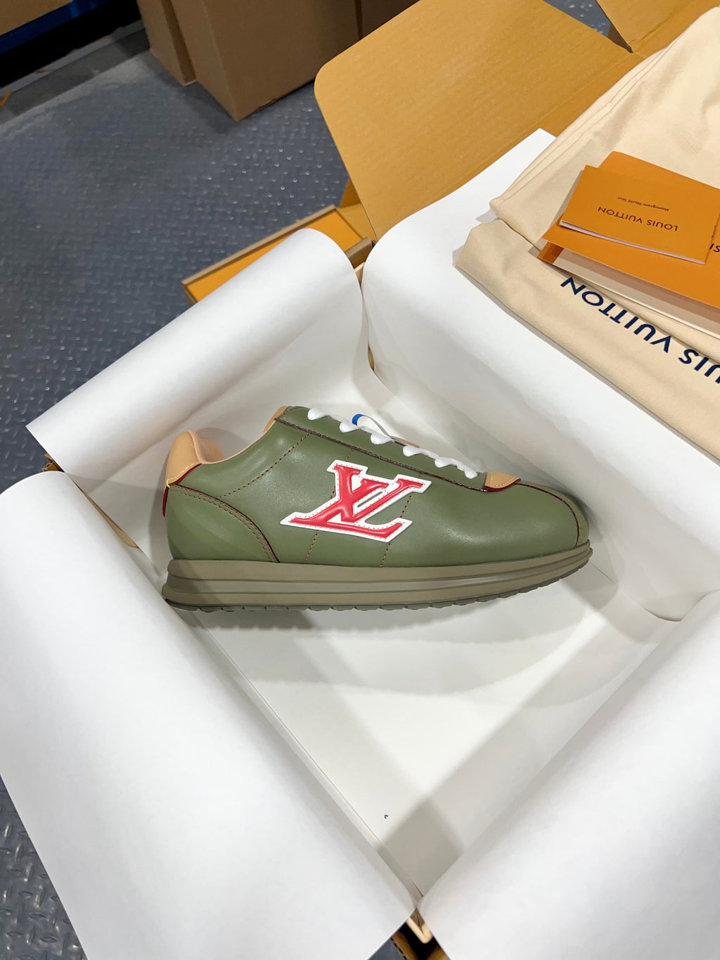 Green leather low-top sneaker with white laces and red LV logo