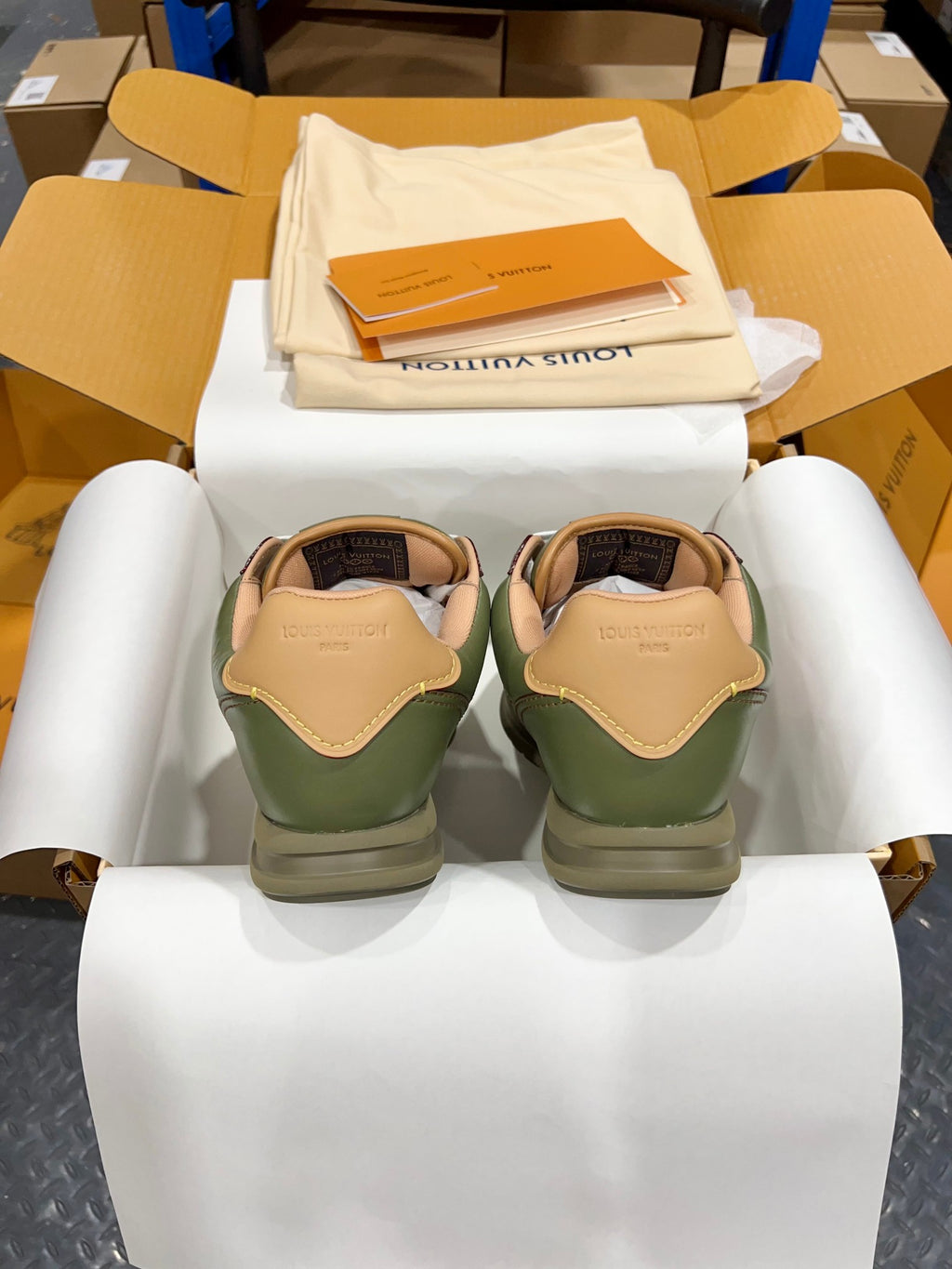 Green leather sneakers with tan heel tabs and white laces in shoebox